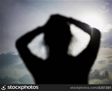 Silhouette of a young woman with her hands in her hair