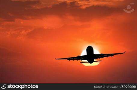 Silhouette of aircraft and orange sky with sun. Landscape with passenger airplane is flying in the sky with clouds at sunset. Travel background. Passenger airliner. Commercial airplane. Business