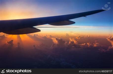 Silhouette of airplane wing on beautiful colorful sunset background, air transportation, traveling and voyage concept