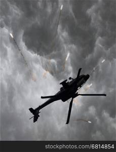 Silhouette of an attack helicopter firing flares, storm is coming