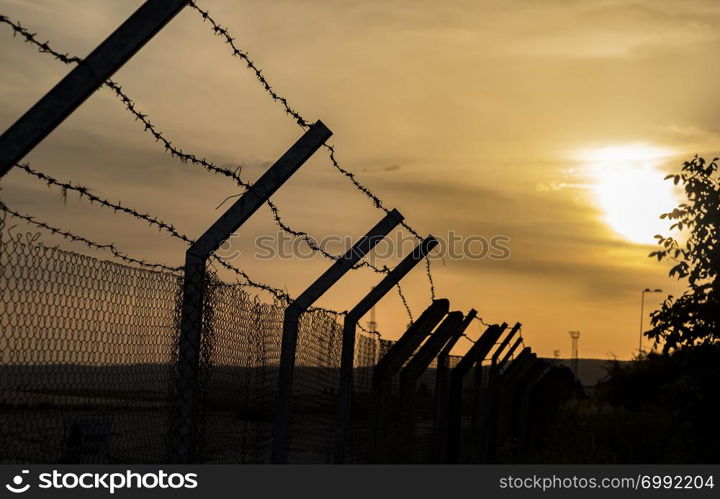 Silhouette of barbed wire fence at sunset