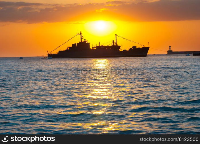 Silhouette of big cargo ship in the port. Sea landscape against sunset