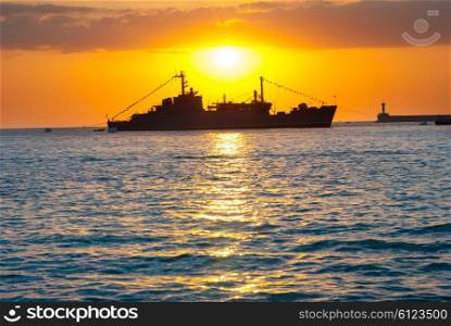 Silhouette of big cargo ship in the port. Sea landscape against sunset