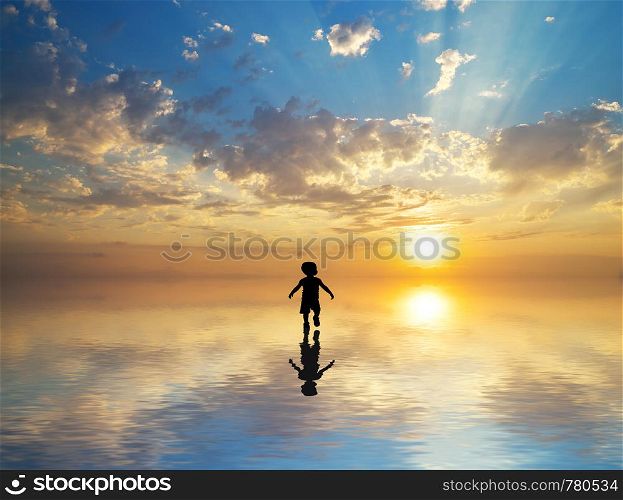 Silhouette of boy walking on water to sun. Conceptual scene.