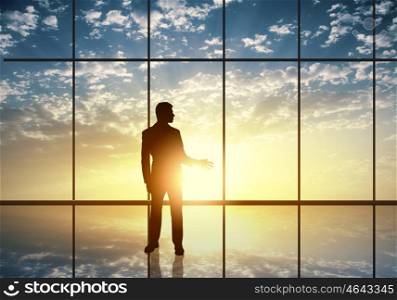 Silhouette of businessman against panoramic office window. Long working hours