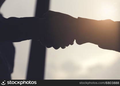 silhouette of businessman handshaking for business cooperation and acquisiton concept, selective focus and vintage tone