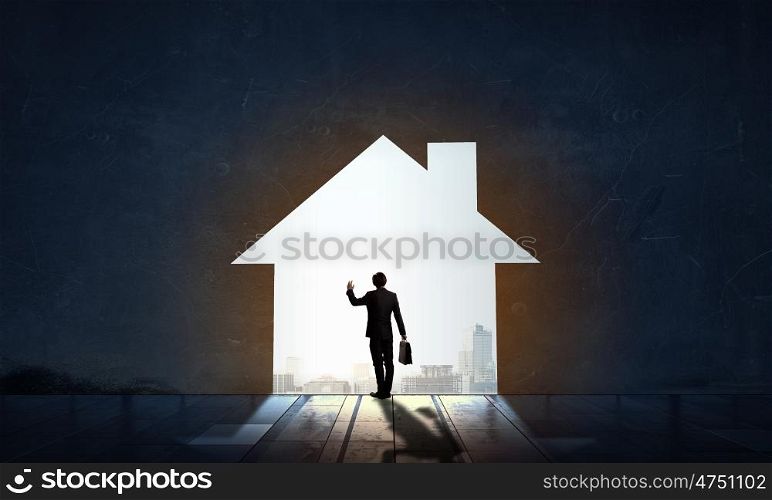 Silhouette of businessman in house doorway. Back view of businessman standing in light of home concept