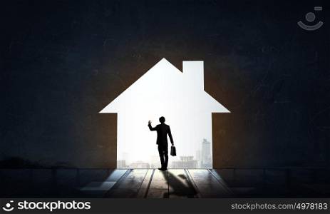 Silhouette of businessman in house doorway. Back view of businessman standing in light of home concept