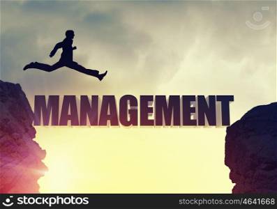 Silhouette of businessman over sunrise. Businessman running on management word bridge over precipice