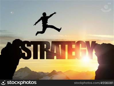 Silhouette of businessman over sunrise. Businessman running on strategy word bridge over precipice