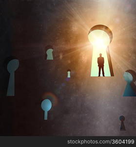 Silhouette of businessman standing in keyhole sun shining above