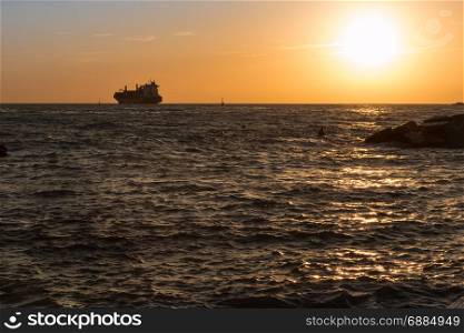 Silhouette of Cargo Boat in Choppy Sea at Sunset
