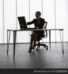 Silhouette of Caucasian businesswoman sitting at desk with computer working.