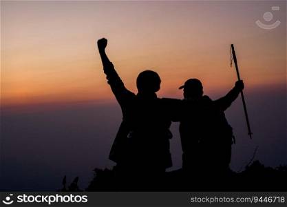Silhouette of cheering hiking couple open arms to the sunrise sit on mountain. Travel Lifestyle wanderlust adventure concept summer vacations outdoor.