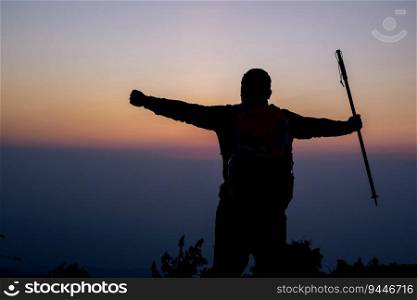 Silhouette of cheering hiking man open arms to the sunrise stand on mountain with copy space. Travel Lifestyle wanderlust adventure concept summer vacations outdoor.