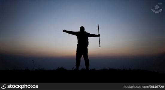 Silhouette of cheering hiking man open arms to the sunrise stand on mountain. Travel Lifestyle wanderlust adventure concept summer vacations outdoor.