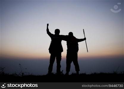 Silhouette of cheering hiking men open arms to the sunrise stand on mountain. Travel Lifestyle wanderlust adventure concept summer vacations outdoor.