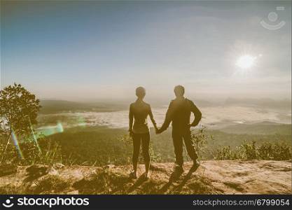 silhouette of couple hiker open arms at mountain peak