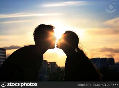 Silhouette of couple kissing.