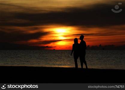 silhouette of couple walking on the beach with beautiful sunrise background