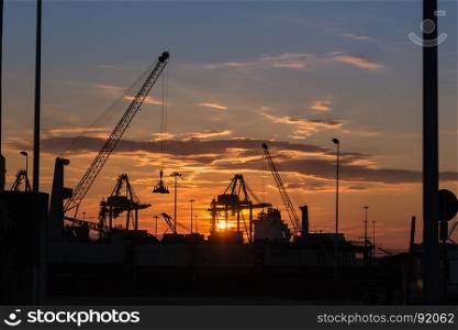 Silhouette of Cranes at Work in Boatyard at Sunset