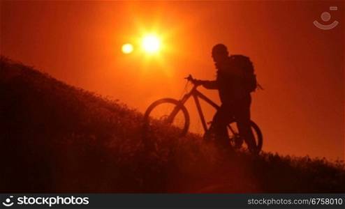 Silhouette of cyclist riding bicycle into the rising sun