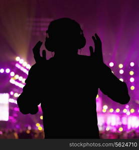 Silhouette of DJ wearing headphones and performing at a night club