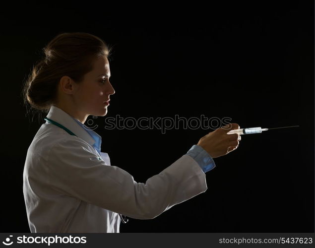 Silhouette of doctor woman using syringe isolated on black