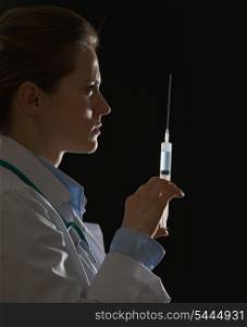 Silhouette of doctor woman with syringe on black background