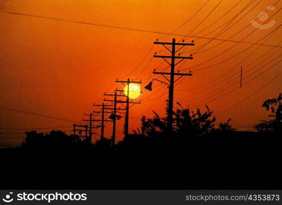Silhouette of electricity pylons and power lines at sunset