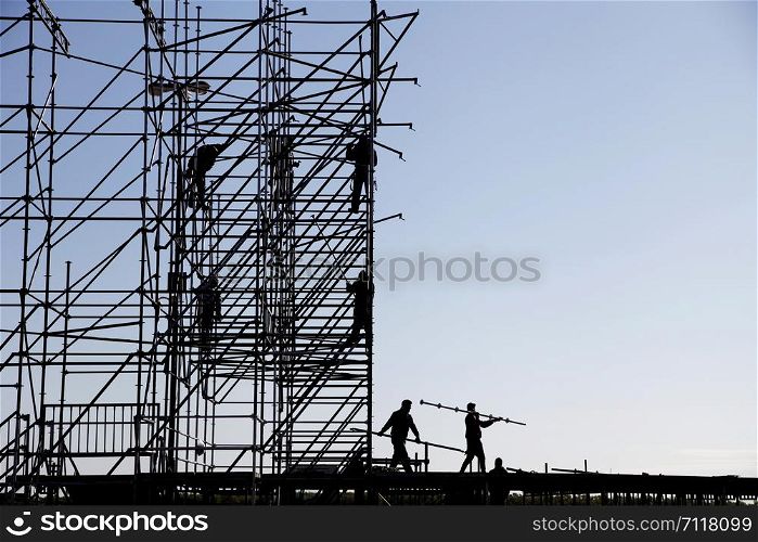 Silhouette of engineer and construction team working at site over sky background, construction concept