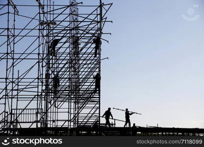 Silhouette of engineer and construction team working at site over sky background, construction concept