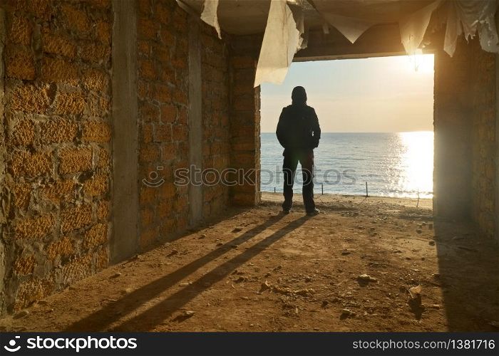 Silhouette of free man. Broken building and sea sunset. Prison escape. Conceptual scene composition.