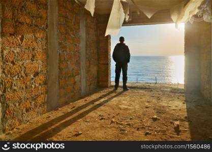 Silhouette of free man. Broken building and sea sunset. Prison escape. Conceptual scene composition.