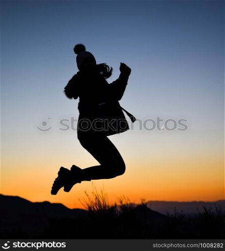 Silhouette of girl jumping against sunset. Silhouette of girl jumping in the middle of nature on winter against sunset