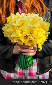 silhouette of girl with red hair with bouquet of daffodils hands.Selective focus. figure girl with bouquet of daffodils in his hands