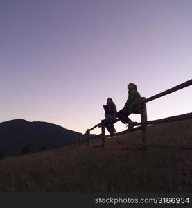 Silhouette of girls on fence