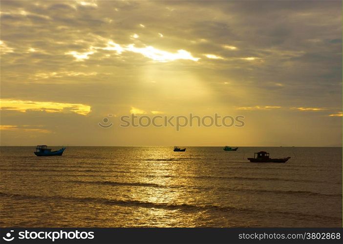 Silhouette of group of fishing boat on sea, seascape at sunrise, sky with cloud, sun ray shine on water make beautiful landscape