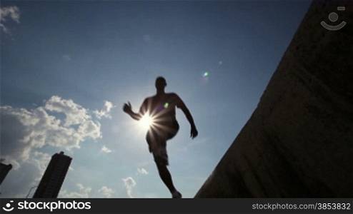 Silhouette of group of young people running and jumping in Havana, Cuba. Low angle view