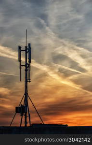 silhouette of GSM transmitters on the roof office building at amazing clouds