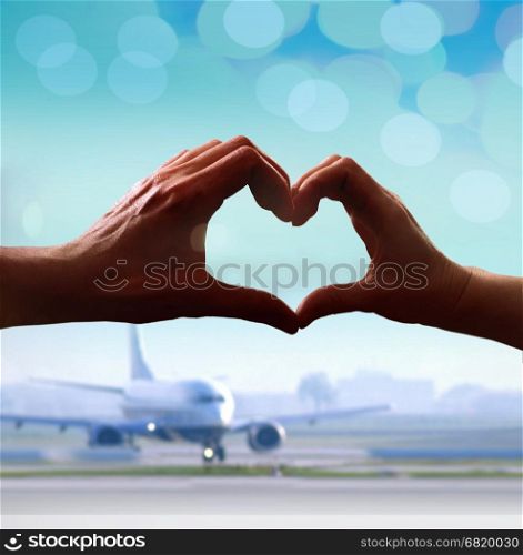 Silhouette of hands in form of heart when sweethearts have touched at airport