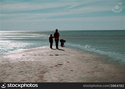 Silhouette of happy children and mother playing on the beach. Concept of friendly family.&#xA;