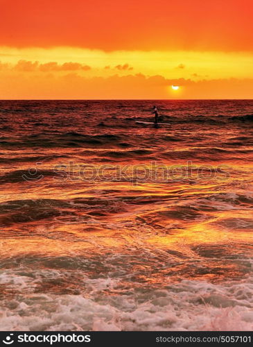 Silhouette of happy surfer in the sea in evening, beautiful orange sunset panorama, extreme sport, active summer vacation concept