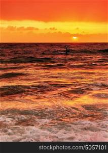 Silhouette of happy surfer in the sea in evening, beautiful orange sunset panorama, extreme sport, active summer vacation concept