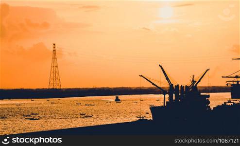 Silhouette of heavy crane tool in ship port and contain stock at sunset scene