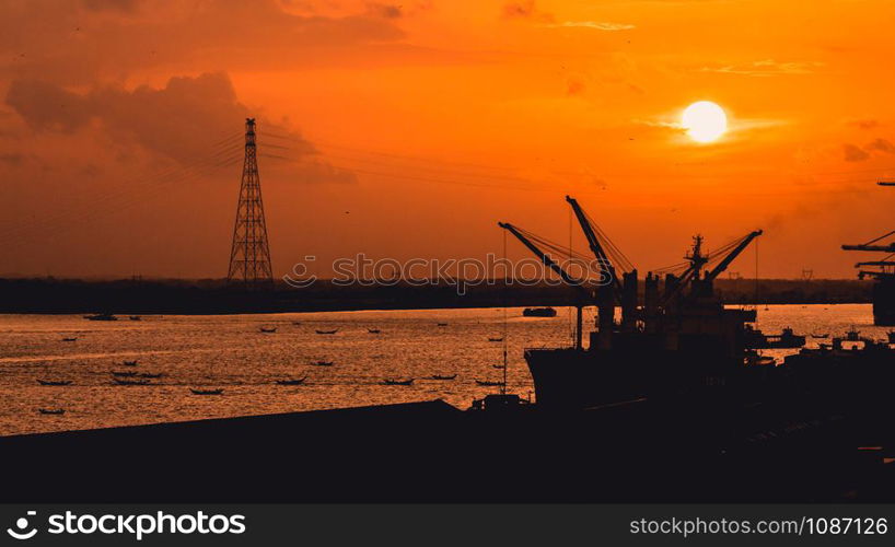 Silhouette of heavy crane tool in ship port and contain stock at sunset scene