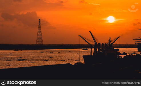 Silhouette of heavy crane tool in ship port and contain stock at sunset scene