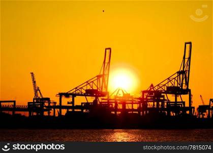 Silhouette of huge commercial harbor against a setting sun on a summer afternoon