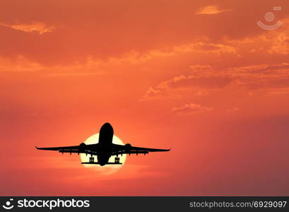 Silhouette of landing aircraft and red sky with sun. Landscape with passenger airplane is flying in the sky with clouds at sunset. Travel background. Passenger airliner. Commercial airplane. Business