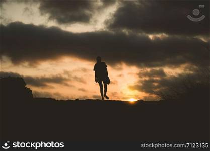 silhouette of lonely person walking with sunset